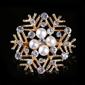 Gold tone snowflake rhinestone pearl brooch detail shot, elegant winter jewelry accessory.
