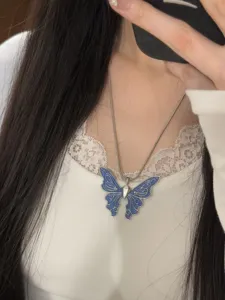 Nahaufnahme einer stilvollen blauen Schmetterling-Halskette mit filigraner Metallkette getragen.