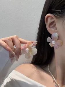 Detailaufnahme von Acryl Perlen Ohrringen mit schimmerndem Blumen Design und Perle.