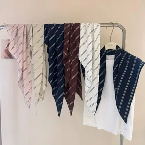 Vue détaillée de foulards triangulaires rayés sur un portant, montrant couleurs et textures.