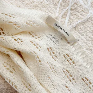 Close-up detail of soft knitted hollow triangular scarf with elegant texture and tag.