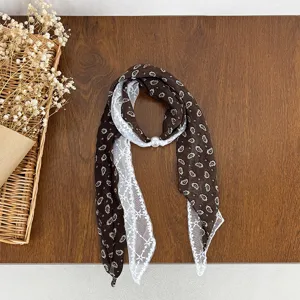 Detail view of women's lace spliced silk scarf with vintage paisley print and pearl ring.