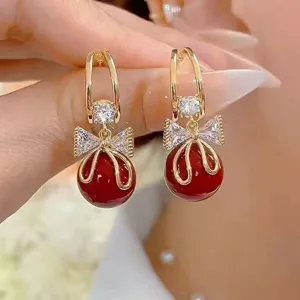 Detaillierte Nahaufnahme eleganter goldfarbener Ohrringe mit funkelnder Schleife und Perle.