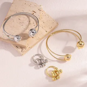 Vista dettagliata di un set di bracciali rigidi e anelli con sfere oro e argento.