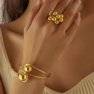 Primo piano dettagliato di un anello dorato con perle lucide e di un elegante bracciale.