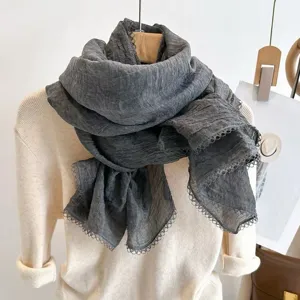 Detail view of the elegant wrinkled lace patchwork thin scarf, soft fabric texture.