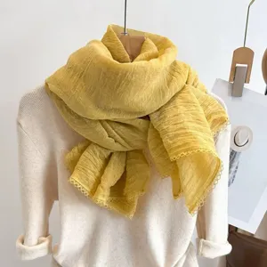 Detail view of a yellow pleated lace scarf, lightweight fabric, elegant Korean style shawl.