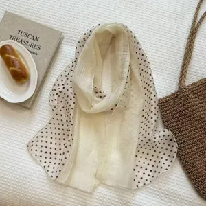 Detail view of beige polka dot sheer scarf, elegant flat lay with lifestyle props.