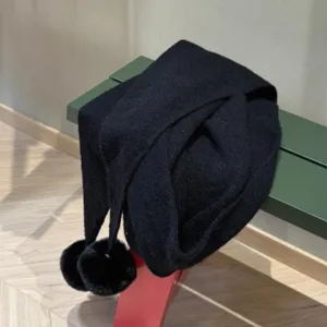 Detailopname van een zwarte gebreide driehoekige sjaal met zachte pompons voor de winter.