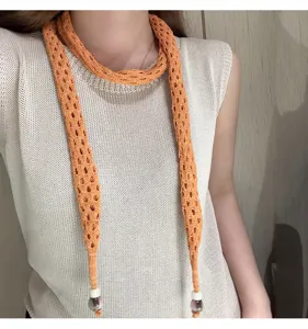 Orange knit hollow-out scarf detail close-up, stylish long neck accessory for modern women.