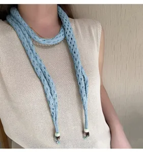 Close-up view of the lightweight blue knitted hollow scarf showing delicate texture and bead detail.