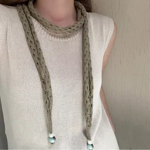 Long knit hollow scarf with bead ends, minimalist style neckerchief detail shot for women.