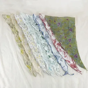 Vue détaillée de foulards triangulaires à imprimé floral avec bords festonnés en diverses couleurs.