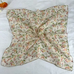 Close-up detail of a retro floral silk square scarf, featuring delicate leaves and flowers.