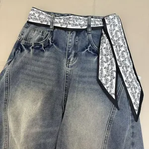 Close-up detail of vintage wash denim jeans featuring black and white paisley print ribbon.