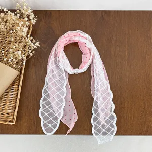 Pink polka dot chiffon scarf with white lace trim and pearl buckle, elegant accessory.