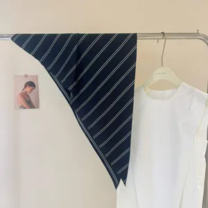 Gros plan d'un foulard triangulaire rayé chic, idéal pour le cou ou la décoration de sac.