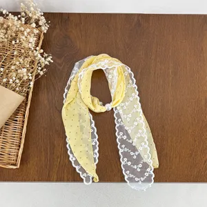 Detailed view of yellow polka dot scarf with white lace trim and pearl ring accessory.