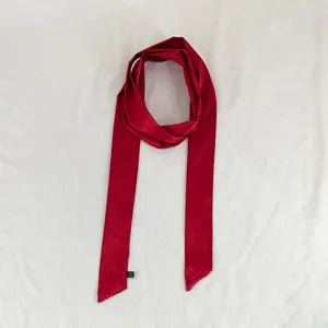 Detailed shot of a sleek red wavy ribbon scarf, perfect for hair tie, neckwear or bag strap.
