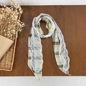 Detailed shot of a stylish plaid silk scarf featuring delicate white lace trim and a pearl buckle.
