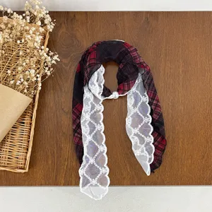 Detailed shot of a red plaid and white lace neck scarf with a delicate pearl buckle.