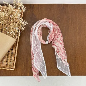 Detail shot of a pink polka dot scarf spliced with white lace and pearl accent, artistic style.