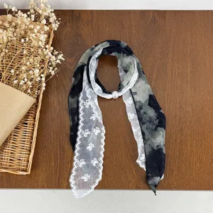 Close-up detail of women's black and white lace splice silk scarf with elegant pearl buckle accent.