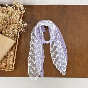 Floral lace scarf detail showing purple floral print, white lace trim and pearl clasp.