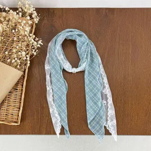 Detailed shot of blue plaid scarf with white lace trim and pearl buckle, cozy desktop scene.