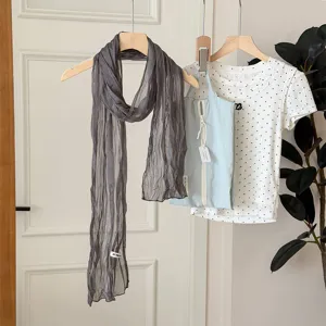 Detailed view of the elegant grey crinkled long scarf hanging with a stylish summer outfit.