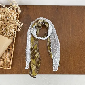 Green plaid scarf with white floral lace trim and pearl buckle, elegant neck accessory.