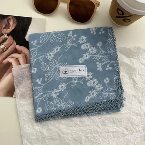 Detail van blauwe katoenen zakdoek met bloemenprint en fijne kanten rand in vintage stijl.