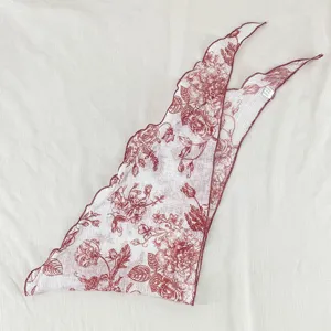 Vue rapprochée détaillée du foulard triangulaire à fleurs rouges, style vintage, tissu doux.