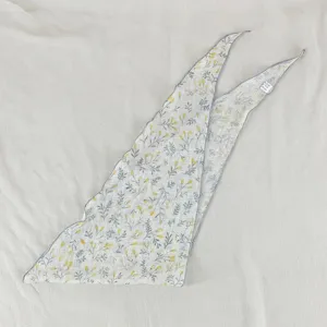 Vue détaillée du foulard triangulaire imprimé de fleurs jaunes et de délicats motifs.