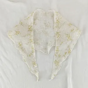 Gros plan détaillé d'un foulard triangulaire floral avec des bords fins sur tissu.