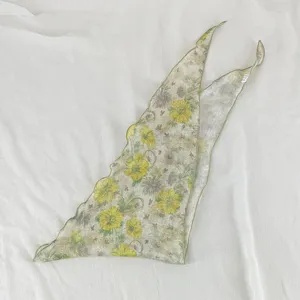 Vue détaillée du bord du foulard triangulaire à imprimé floral jaune vintage et sa texture.