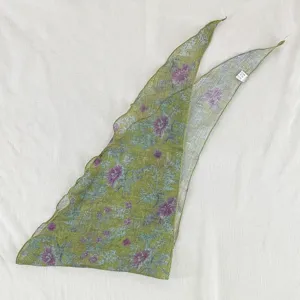 Vue détaillée du foulard triangulaire à fleurs vertes montrant la texture du tissu.