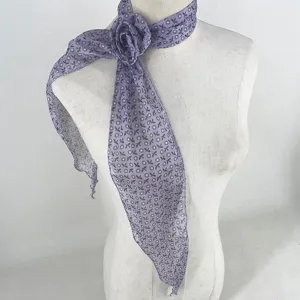 Vue de détail d'un foulard en soie violette avec fleur de rose 3D amovible pour le cou.