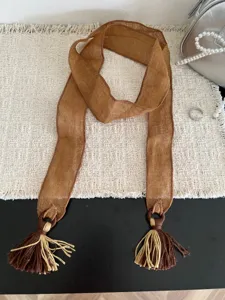 Detail view of the brown sheer ribbon scarf with chic double tassels and wooden ring accents.
