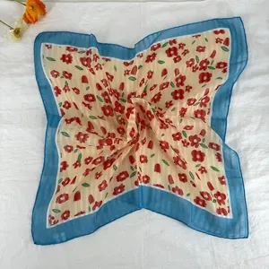 Close up of retro floral square scarf with blue border, vintage neckerchief detail.