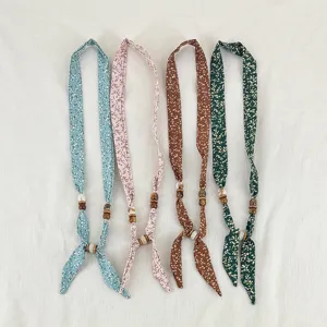 Detailed view of floral skinny scarf necklace with wooden beads, vintage fabric necktie accessories.