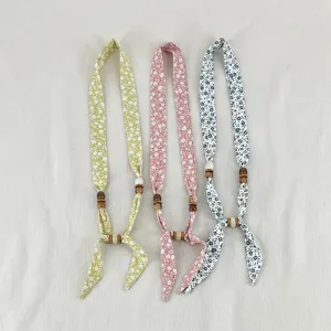 Vintage floral fabric necklace with wooden beads, elegant detailed view of small scarf accessory.