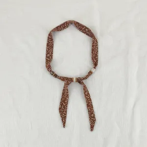 Close-up detail of the retro brown floral print scarf necklace with delicate beaded accents.