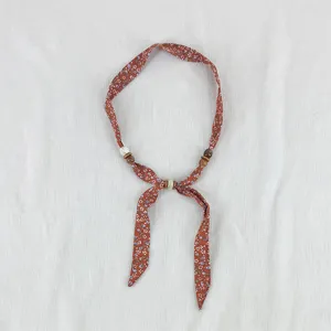 Detail view of the vintage floral silk scarf necklace with wooden and white beads accessory.