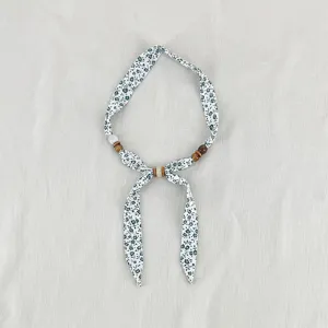 Detailed view of vintage floral fabric scarf necklace with natural wooden and stone beads decoration.