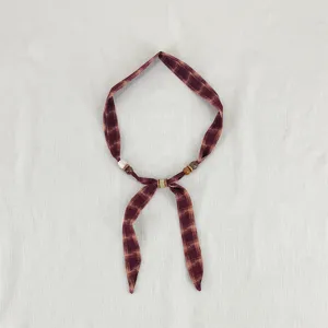 Detail shot of retro plaid fabric scarf necklace with beads, showing unique artisanal design.