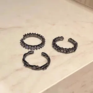 Conjunto de anillos abiertos negros estilo punk con cristales morados y cruz.