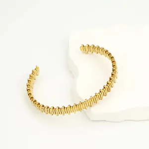 Golden serrated bracelet detail showcasing unique metallic block texture and polished finish.