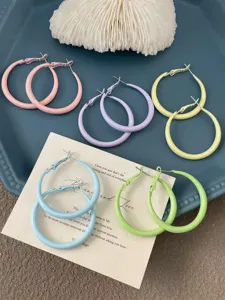Detailed closeup of colorful macaron hoop earrings in various sweet pastel shades on a tray.