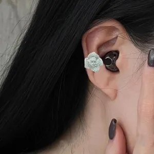 Close-up of sparkling rhinestone camellia flower earphone clip accessory for stylish wireless earbuds.